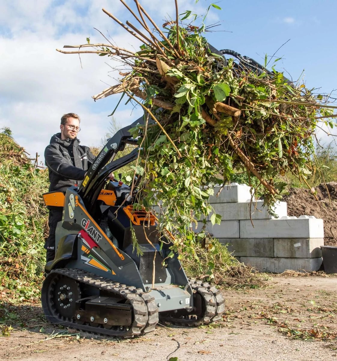 Giant mini skid steer lifting a pile of brush