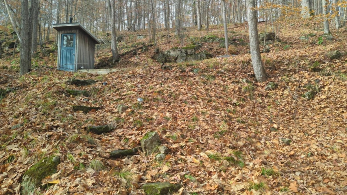 Rocky slope with exposed Canadian Shield bedrock and a small outbuilding